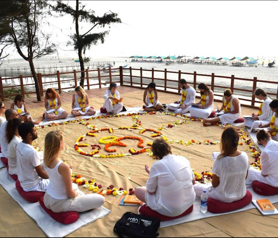 Students participating in a 200-hour yoga teacher training in Goa, practicing asanas outdoors at Diksha Yoga Hippie Paws Wellness Resort, surrounded by lush greenery.